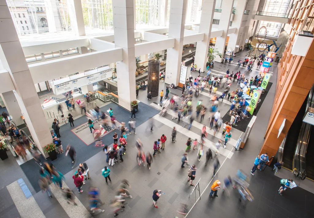 Delegates moving through the concourse of a large convention centre during an industry event
